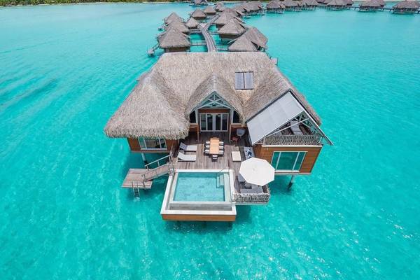 Ein InterContinental Bora Bora Wasserbungalow mit Pool und Sonnenschirm.