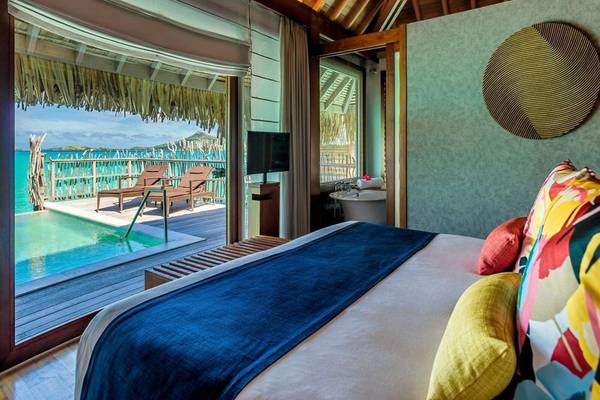 Ein komfortables Bett mit farbenfrohen Kissen und Blick auf das Meer im InterContinental Bora Bora.