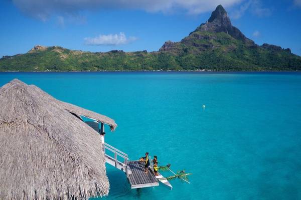 Aussicht auf das InterContinental Bora Bora Resort und Thalasso Spa mit kristallklarem Wasser und Bergen im Hintergrund.