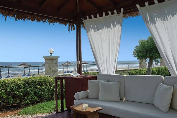 Außenbereich des Atlantica Caldera Palace mit einem Sofa, Tisch, Blick auf den Strand und Meer.