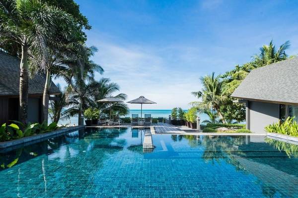 Außenpool des KC Grande Resort Koh Chang mit Blick auf das Meer und tropischen Bäumen.