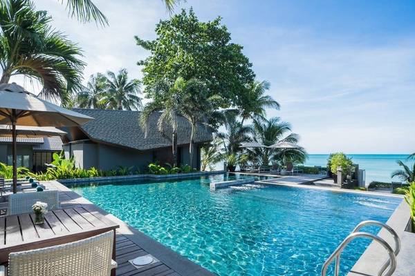 Außenbereich des KC Grande Resort Koh Chang mit Swimmingpool, Sonnenliegen und Palmen.