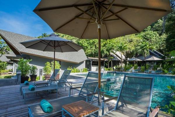 Pool-Lounge-Bereich im KC Grande Resort Koh Chang mit Sonnenschirmen und Liegestühlen.