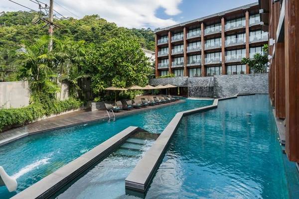 Außenpool des KC Grande Resort Koh Chang mit Loungeliegen und Bäumen.