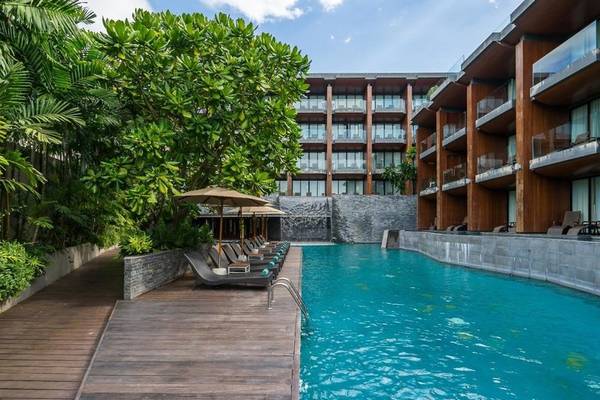 Poolbereich des KC Grande Resort Koh Chang mit Loungeliegen und großen Sonnenschirmen.