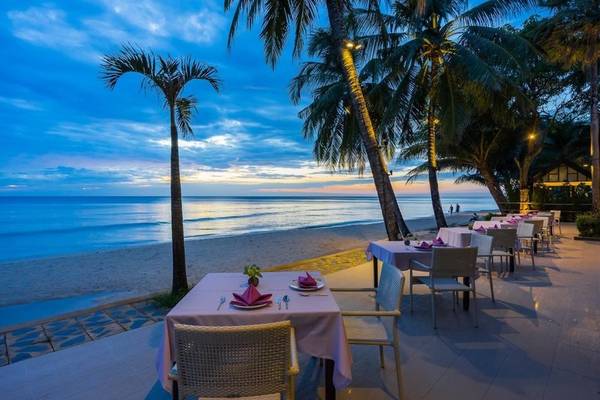 Außenrestaurant des KC Grande Resort Koh Chang mit Tischen am Strand bei Sonnenuntergang