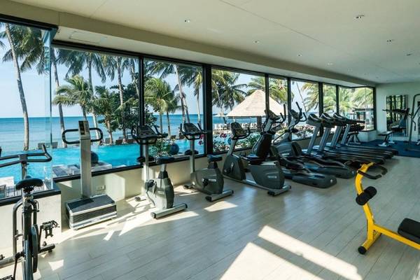 Fitness-Center im KC Grande Resort Koh Chang mit Aussicht auf das Meer und Palmen.