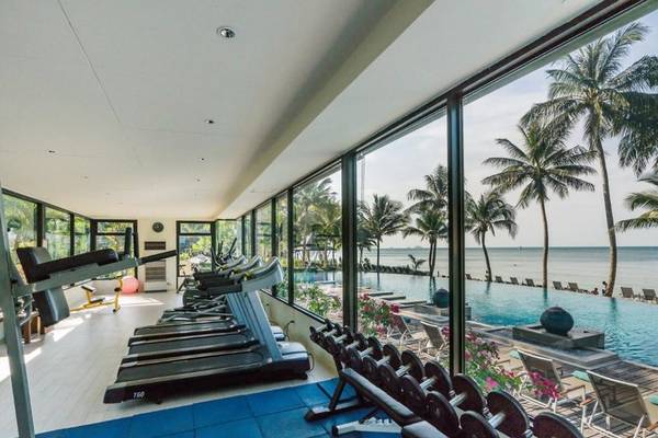 Fitnessbereich im KC Grande Resort Koh Chang mit Blick auf den Ozean und Palmen.