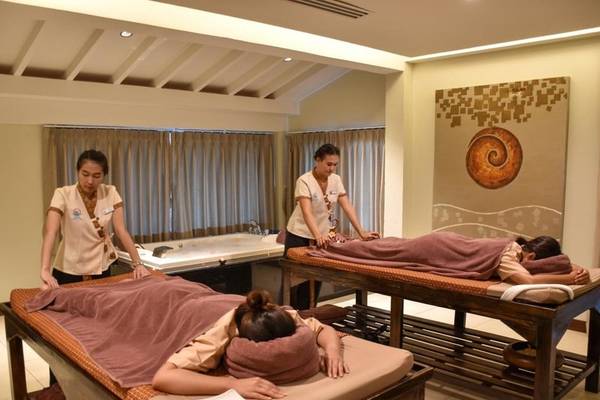 Massage Behandlung im KC Grande Resort Koh Chang mit zwei Frauen, die Kunden auf Massagetischen betreuen.