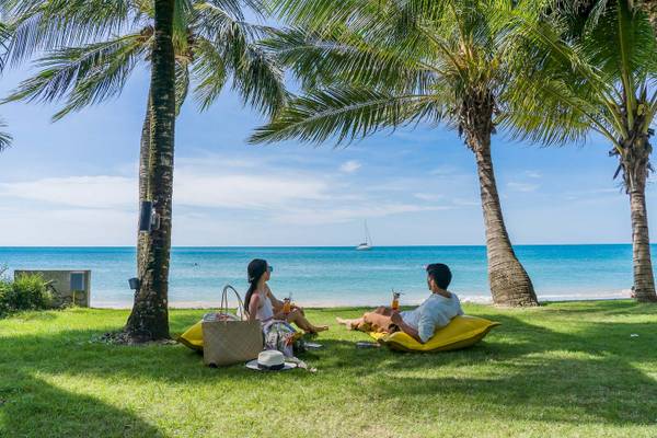 Ein Paar sitzt auf gelben Kissen am Strand vor dem KC Grande Resort Koh Chang.