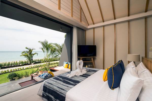 Hotelzimmer mit großem Fenster und Meerblick, Bett mit blauen Kissen und Fernseher