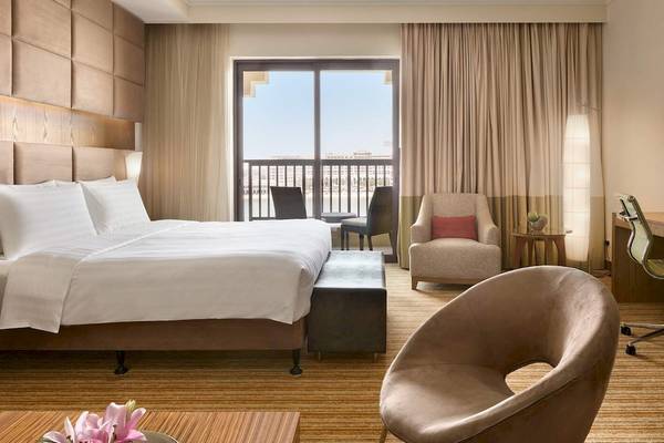 Schlafzimmer im Traders Hotel Qaryat Al Beri mit Bett, Schreibtisch und Balkon
