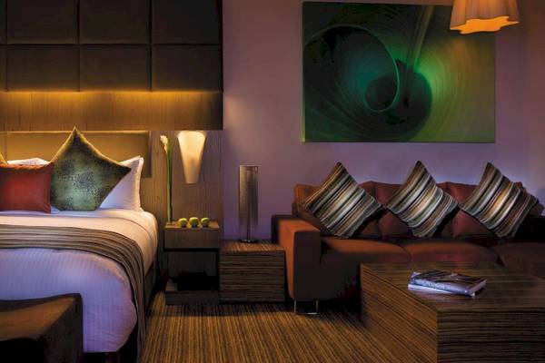 Hotelzimmer im Traders Hotel Qaryat Al Beri mit Bett, Sofa und moderner Einrichtung.
