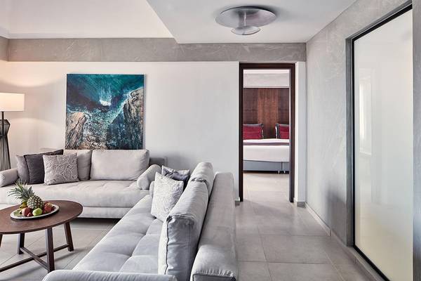Wohnzimmer des Atlantica Caldera Palace Hotels mit zwei Sofas, einem Tisch mit Obst und einem Gemälde an der Wand.