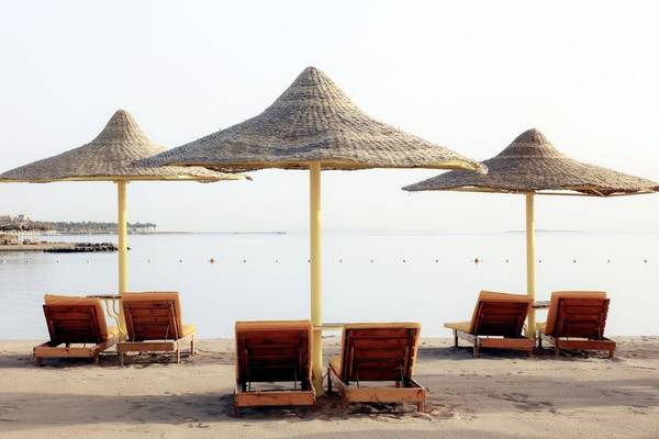 Strand mit Lounge-Stühlen unter Sonnenhüten und Blick auf das Meer
