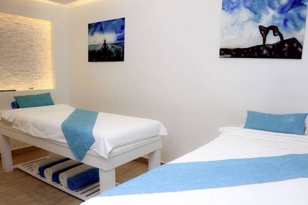 Zwei Betten im Spa-Bereich des Lemon & Soul Garden Makadi Hotels mit weißen Laken und blauen Kissenbezügen.