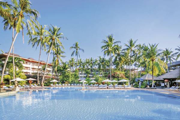 Außenpool des Prama Sanur Beach Bali Hotels mit Sonnenliegen und Palmen.