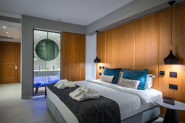 Doppelbett-Zimmer im Atlantica Caldera Palace Hotel mit blauen Kissen und Holzwänden.
