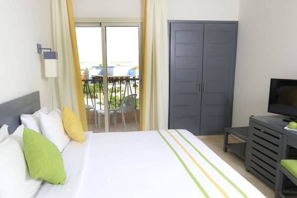 Schlafzimmer mit Balkon im Lemon & Soul Garden Makadi Hotel, ausgestattet mit einem großen Bett, Fernseher und Blick auf Terrasse.