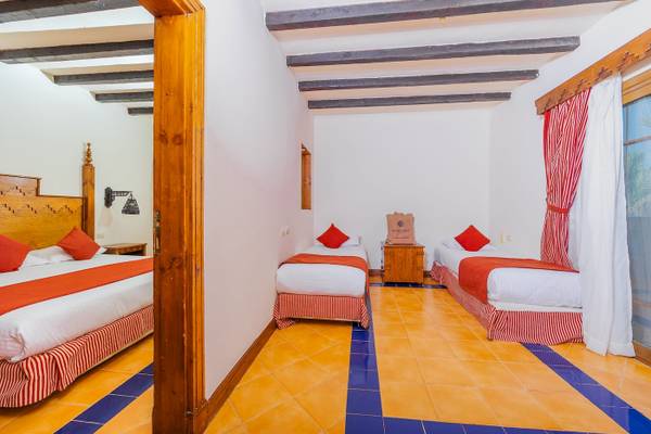 Dreibettzimmer im Grand Makadi Hotel mit blauen und gelben Fliesen und drei Betten.