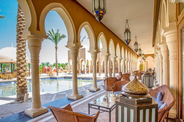 Loungebereich des Grand Makadi Hotels mit bogenförmigen Säulen und einem Pool im Hintergrund.
