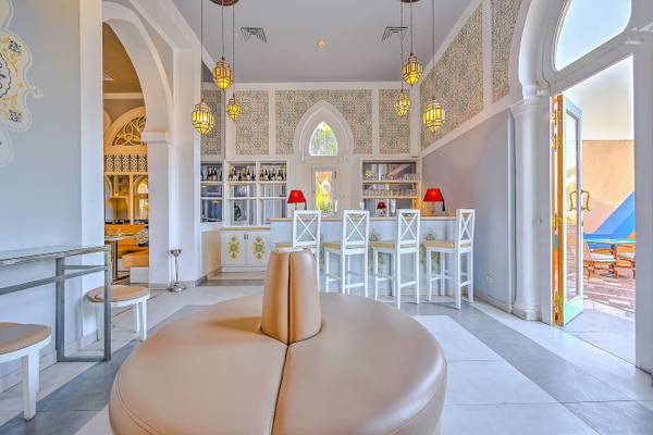 Innenansicht der Bar im Grand Makadi Hotel mit weißen Stühlen und thematischen Wanddekorationen.