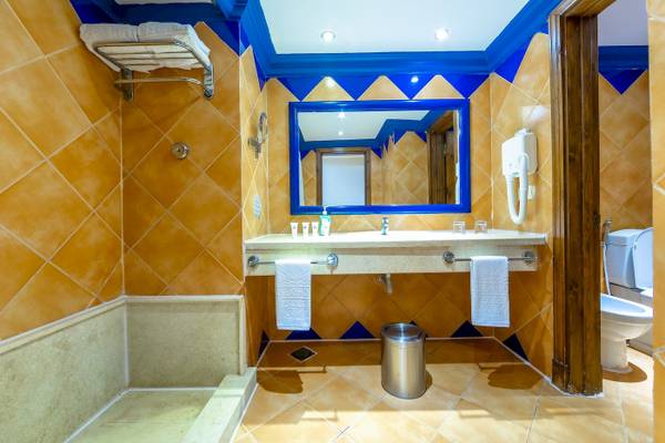 Badezimmer im Grand Makadi Hotel mit blauen Akzenten, Waschbecken, Spiegel und Toilette.