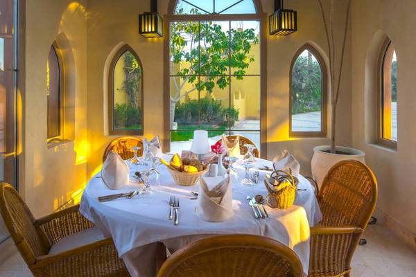 Essenbereich im Grand Makadi Hotel mit Tisch, Stühlen und Blick auf einen Garten.