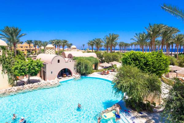 Luftaufnahme des Pools im Grand Makadi Hotel mit Palmen und Meer im Hintergrund.