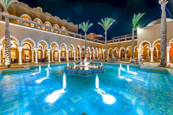 Nachtansicht des Grand Makadi Hotels mit einem Pool und Brunnen im Vordergrund.