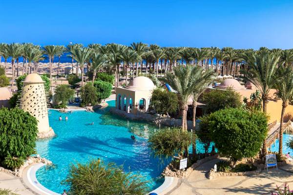 Luftaufnahme des Swimmingpools im Grand Makadi Hotel mit mehreren Schwimmern und tropischen Bäumen.