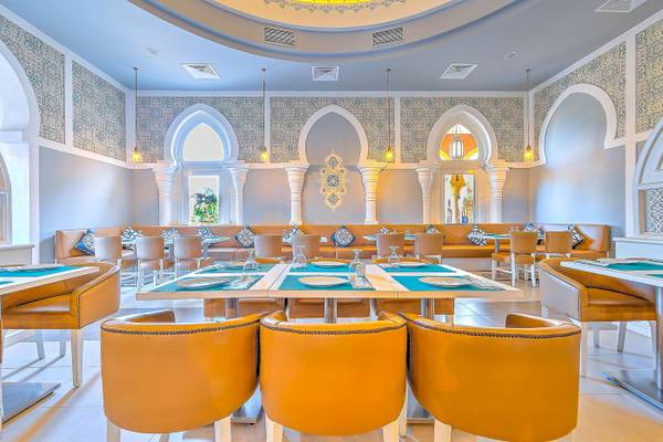 Innenraum des Grand Makadi Hotels mit Restauranttischen und blauen Kissen.