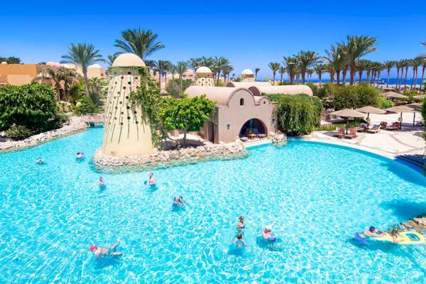 Außenansicht des Swimmingpools im Grand Makadi Hotel mit Gästen und Palmen