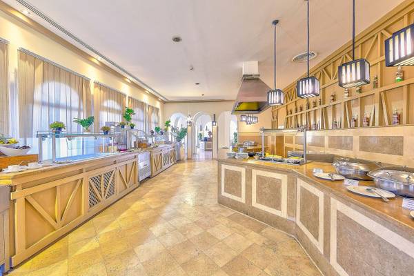 Innenansicht des Speisesaals im Grand Makadi Hotel mit langen Tischen, Buffets und hängenden Lampen.