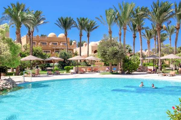 Ein Swimmingpool mit mehreren Sonnenschirmen und Liegestühlen am Grand Makadi Hotel