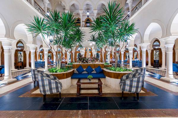 Foyer des Grand Makadi Hotels mit großen grünen Palmen und blauen Sofas.