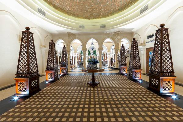 Der Eingangsbereich des Grand Makadi Hotels mit geometrischem Musterboden und dekorativen Holzsäulen.