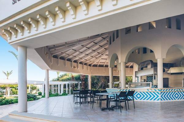 Terrasse des Iberostar Selection Royal El Mansour Hotels mit Tischen und Stühlen unter einem Dach.
