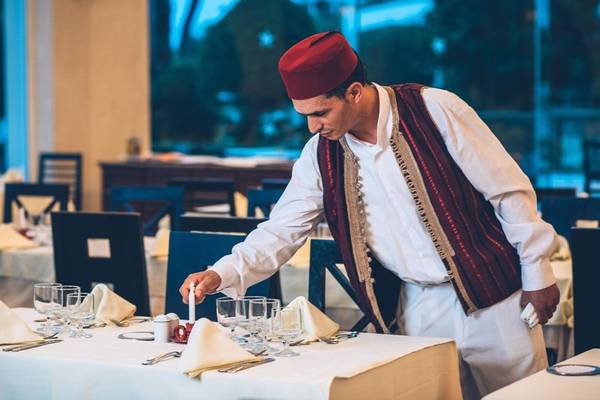 Mann im roten Hut bereitet einen Tisch im Restaurant des Iberostar Selection Royal El Mansour vor.
