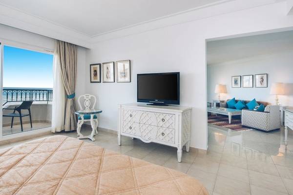 Ein modernes Hotelzimmer im Iberostar Selection Royal El Mansour mit einem Bett, Fernseher, und einem Balkon mit Blick auf das Meer.