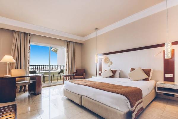Ein elegantes Hotelzimmer im Iberostar Selection Royal El Mansour mit einem großen Bett, einem Schreibtisch und einem Balkon.