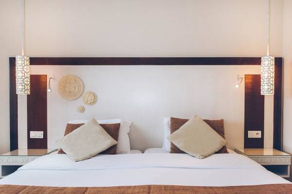 Doppelbett im Hotelzimmer des Iberostar Selection Royal El Mansour mit weißen und braunen Kissen.