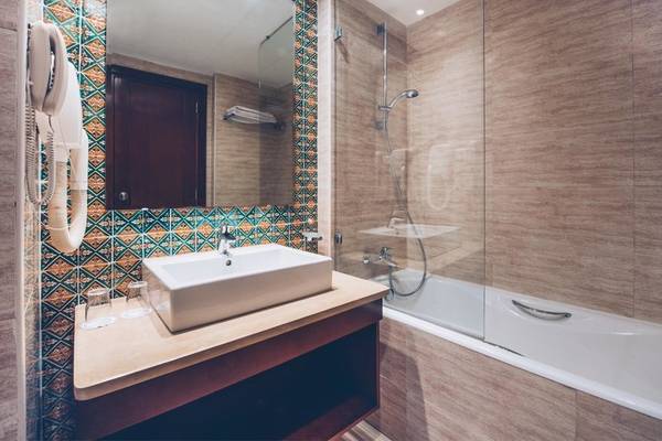 Badezimmer im Hotel Iberostar Selection Royal El Mansour mit Badewanne, Waschbecken und Regendusche.