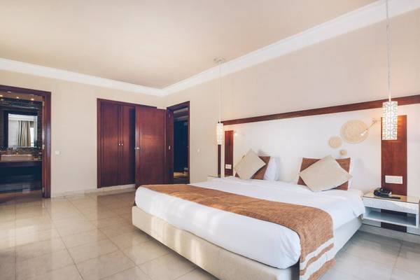 Schlafzimmer im Iberostar Selection Royal El Mansour Hotel mit einem großen Bett und offenen Türen.