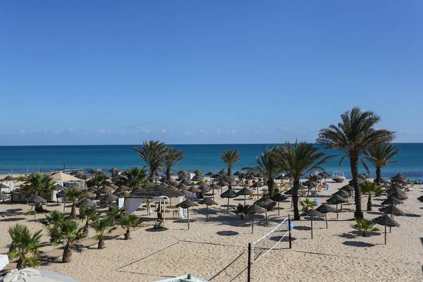 Strandaussicht des Paradis Palace Hotels mit vielen Sonnenschirmen und einem Volleyballnetz.