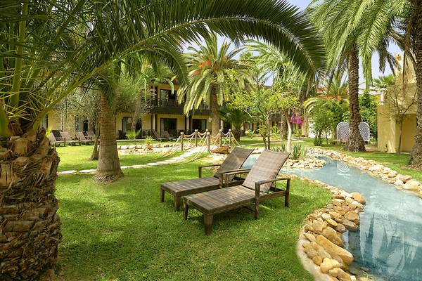 Gartenbereich des Paradis Palace Hotels mit zwei Lounge-Sesseln und einem Wasserlauf.