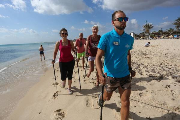 Gruppe von Gästen und ein Betreuer wandern am Strand des Paradis Palace Hotels