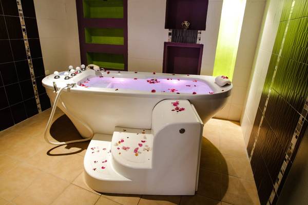 Badezimmer im Paradis Palace mit einer Badewanne voller Rosenblättern und einem gefliesten Boden.