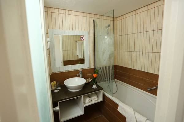 Badezimmer im Paradis Palace Hotel mit Badewanne, Waschbecken und Spiegel.