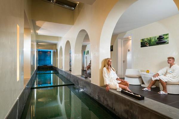 Das Relax-Bereich des Iliade Djerba by Magic Hotels mit einem Schwimmbad und zwei Personen in Bademänteln.